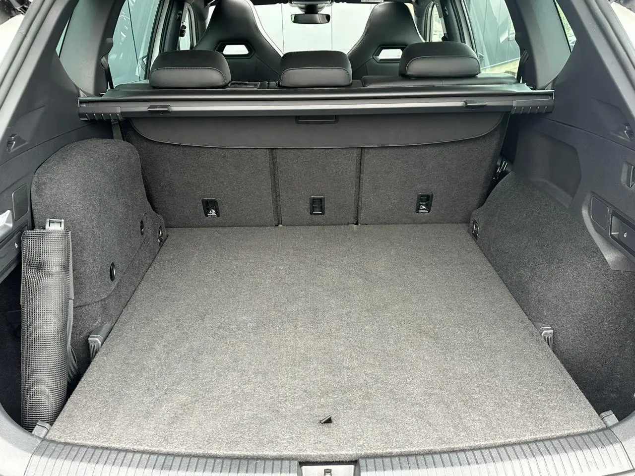 Coffre spacieux du SEAT Tarraco blanc Oryx vu de l'arrière avec banquette arrière et cache-bagages déployé.