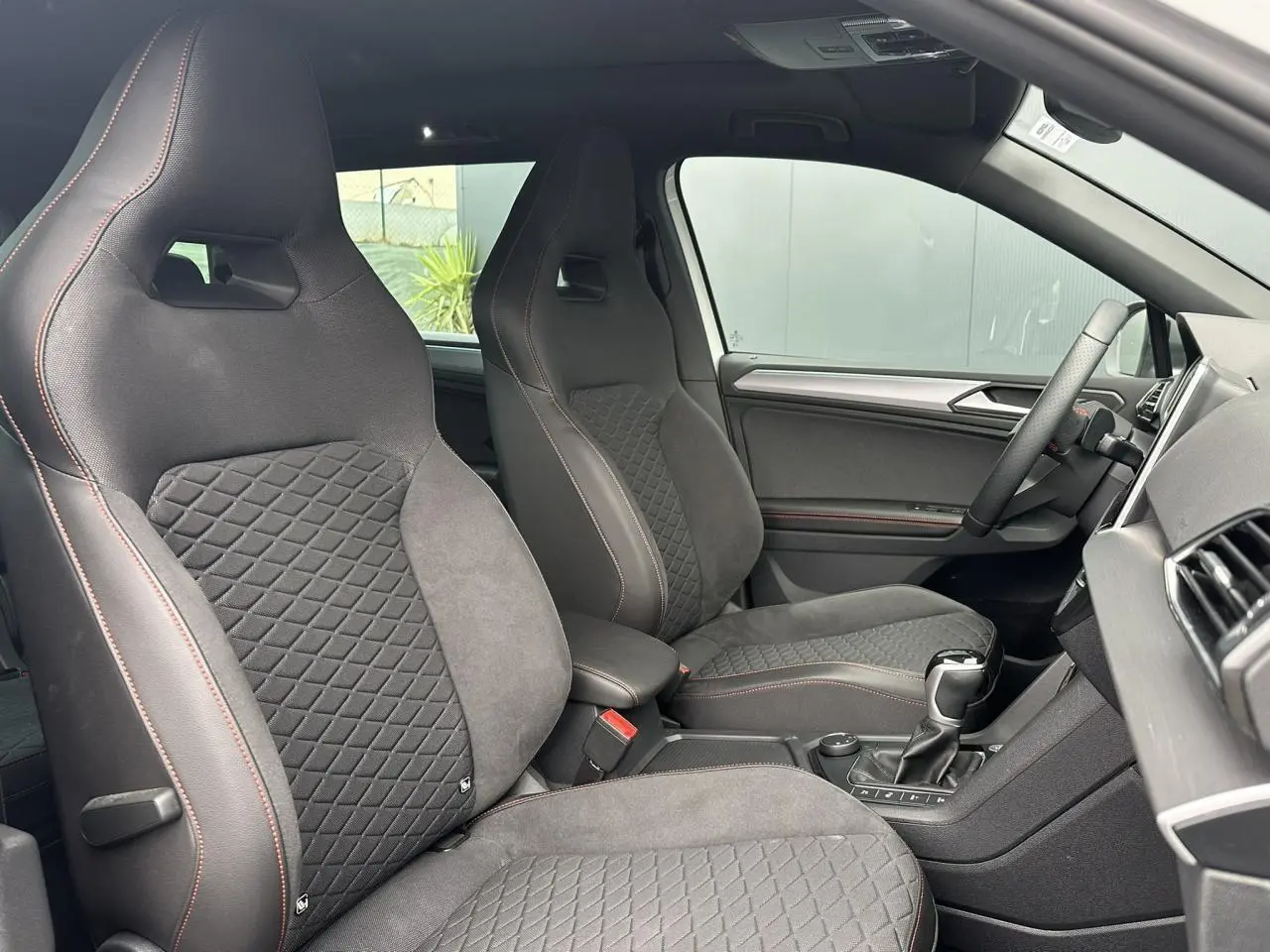 Intérieur du SEAT Tarraco 2024, vue côté droit sur sièges sport noirs avec surpiqûres rouges et volant cuir multifonction.