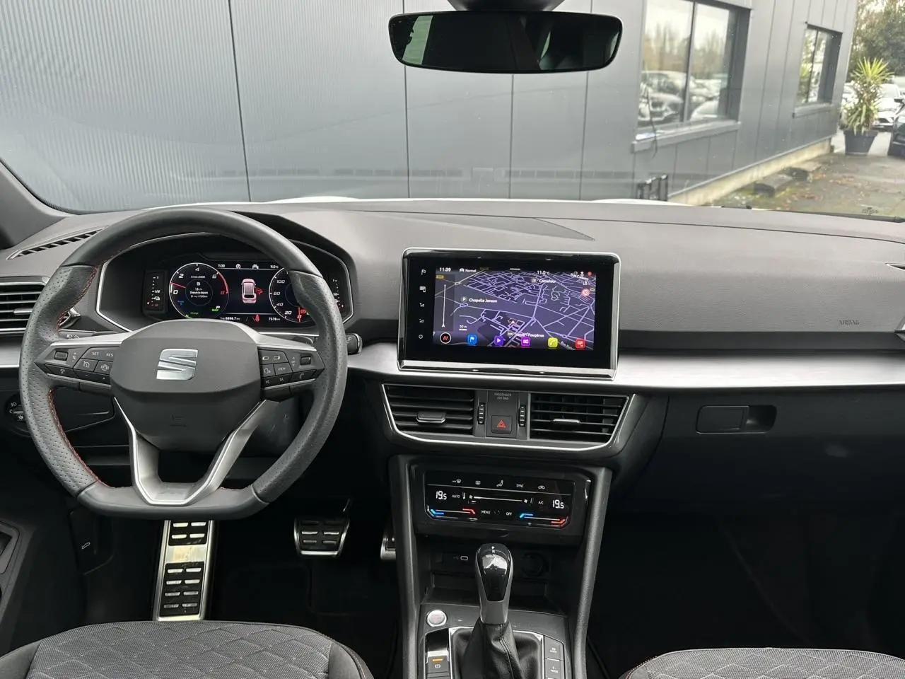 Vue intérieure du tableau de bord du SEAT Tarraco blanc, avec volant sport cuir multifonction et écran tactile navigation.
