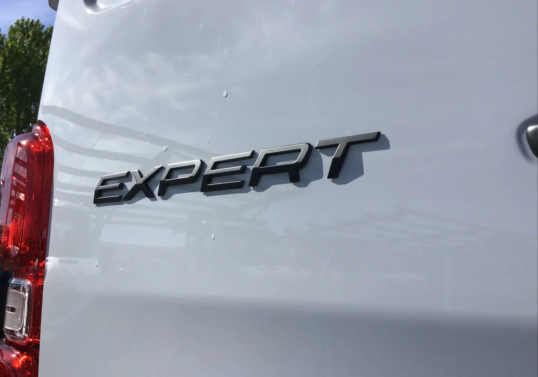 Gros plan sur l'arrière gauche blanc du Peugeot Expert Fourgon avec logo noir "EXPERT" et feu arrière rouge visible.