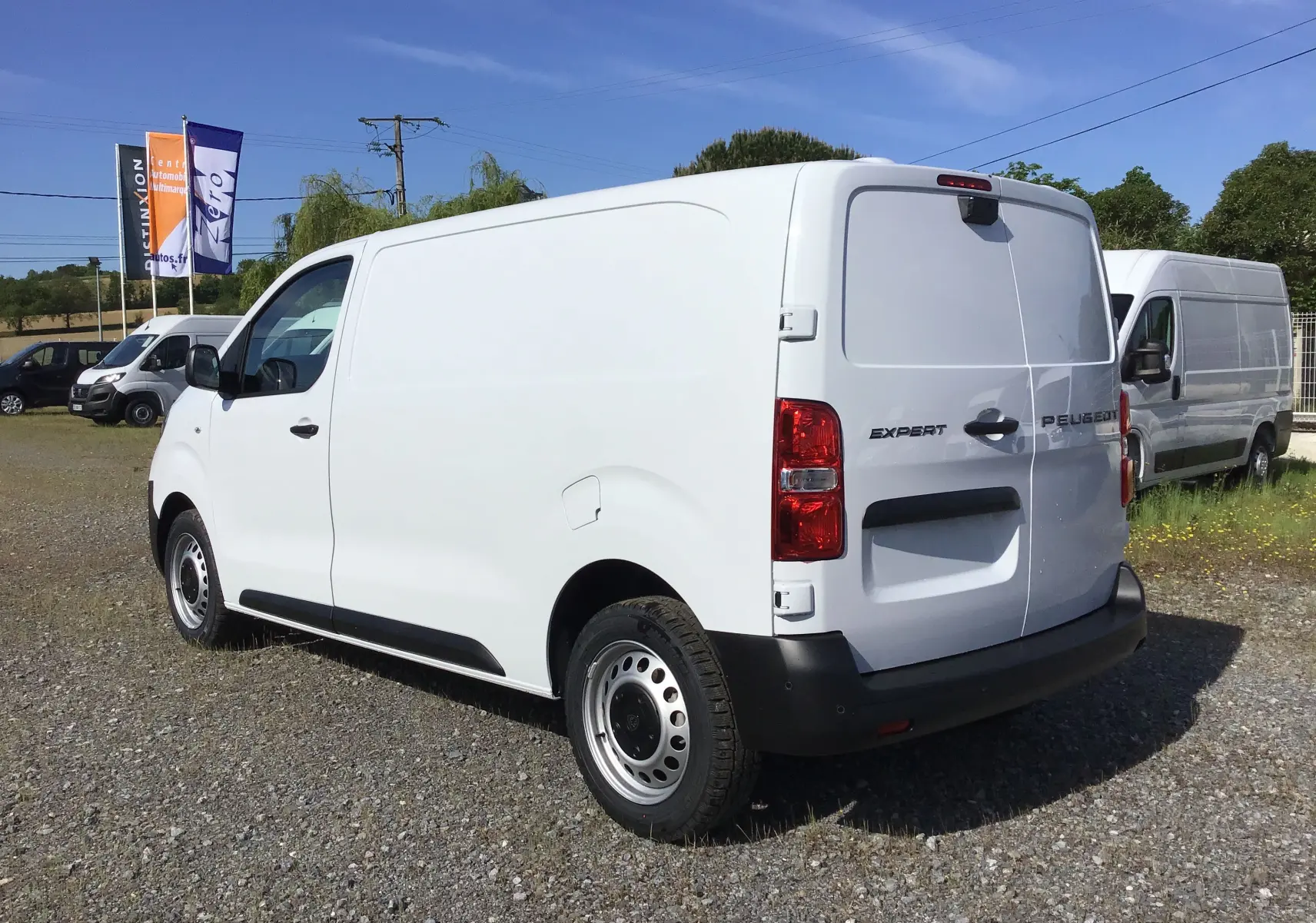 Vue 3/4 arrière droite d'un Peugeot Expert Fourgon blanc avec portes arrière fermées sur un terrain extérieur.