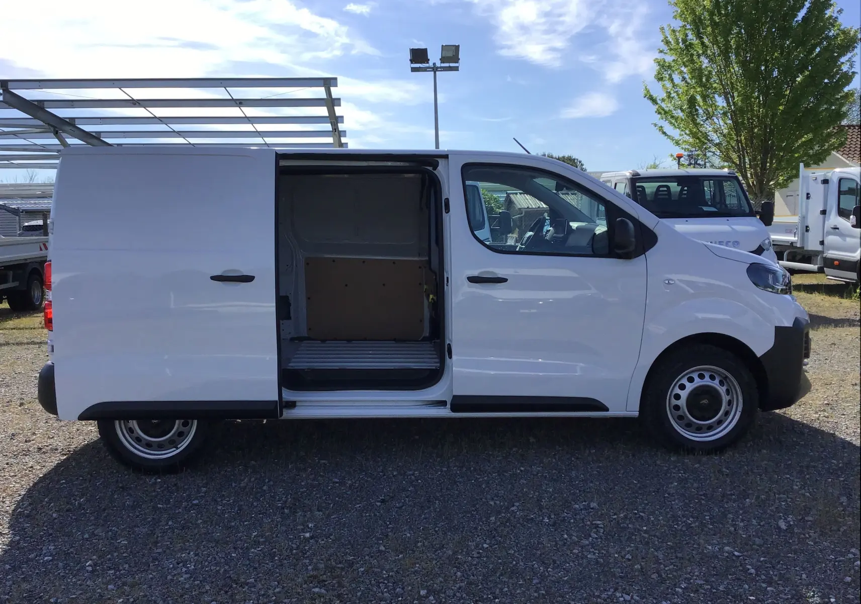 Profil côté gauche du Peugeot Expert Fourgon blanc 2025 avec porte latérale coulissante ouverte montrant l’espace de chargement vide.