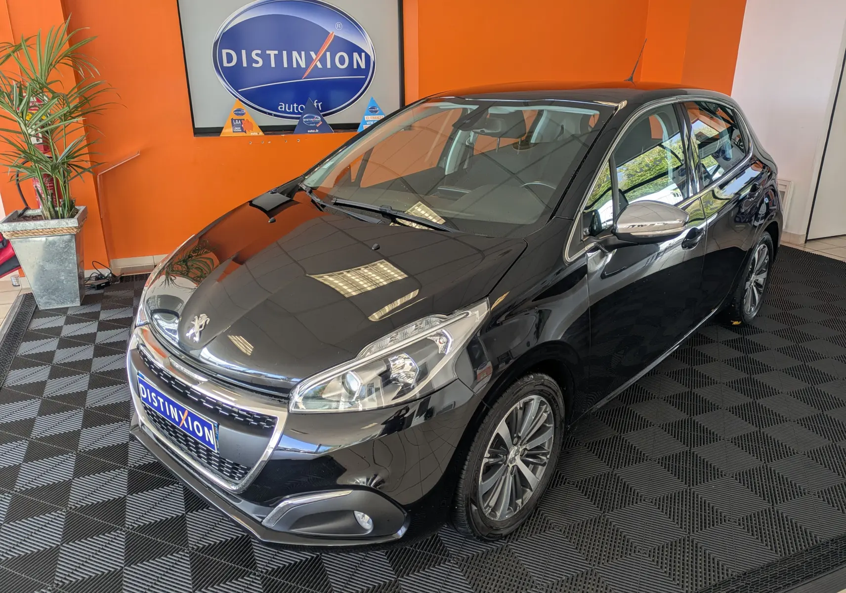 Peugeot 208 Allure noir vue 3/4 avant droit en intérieur, avec jantes alliage et rétroviseurs chromés.