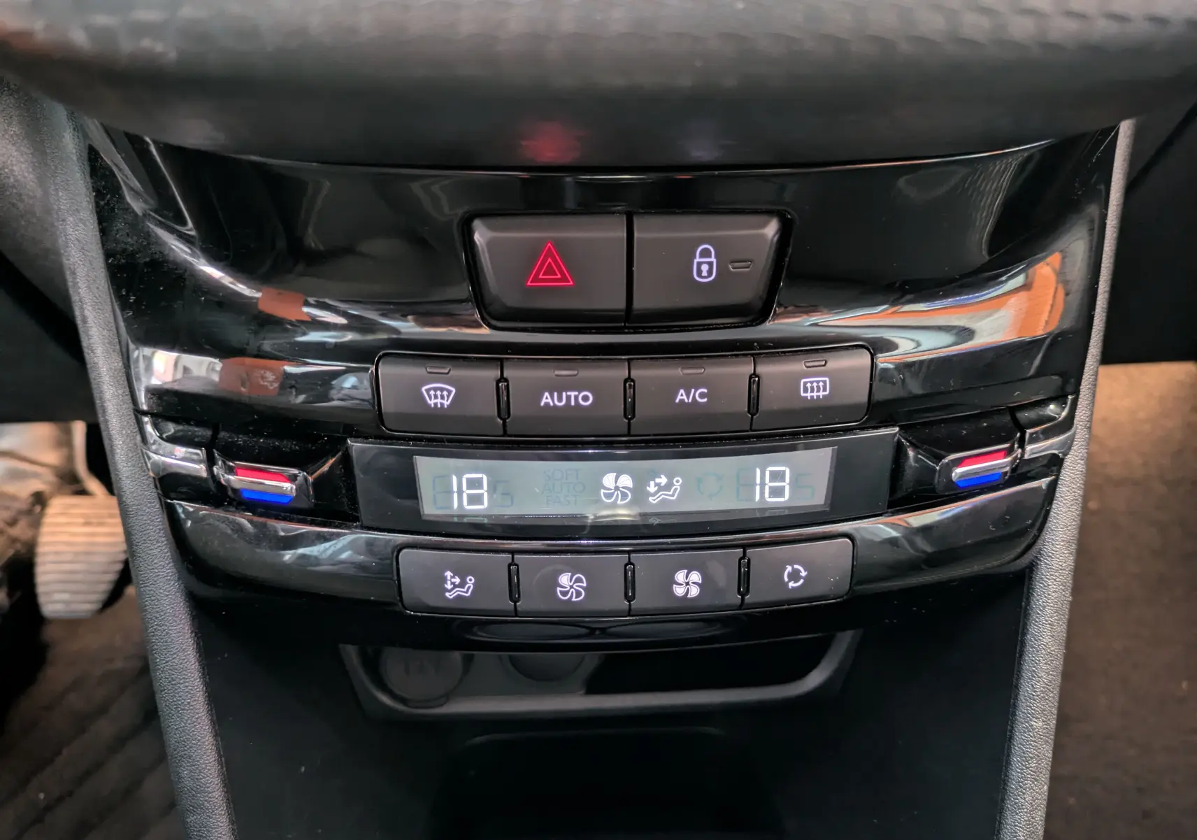 Gros plan sur la console centrale noire de la Peugeot 208 Allure 2019, montrant les commandes de climatisation digitale.