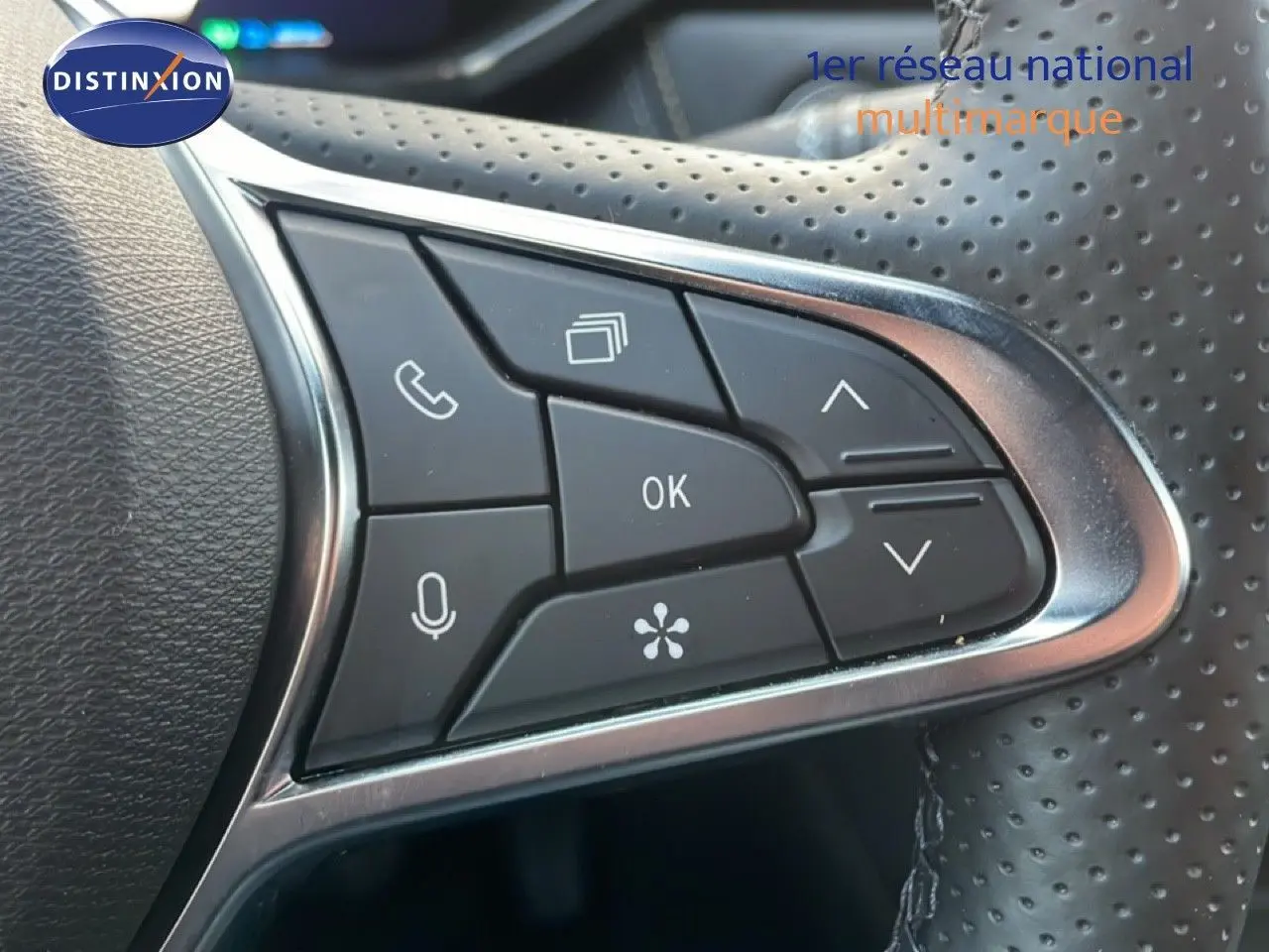 Gros plan sur les commandes multifonctions du volant perforé noir du Renault Symbioz gris Cassiopée Métal.