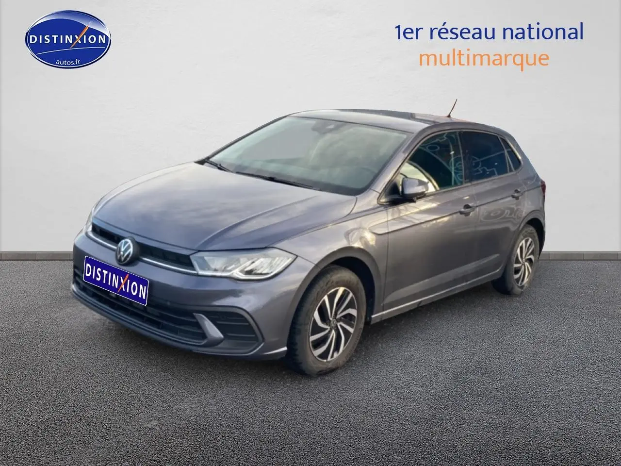 Volkswagen Polo gris cendre vue 3/4 avant droit sur sol gris avec jantes alliage distinctives.