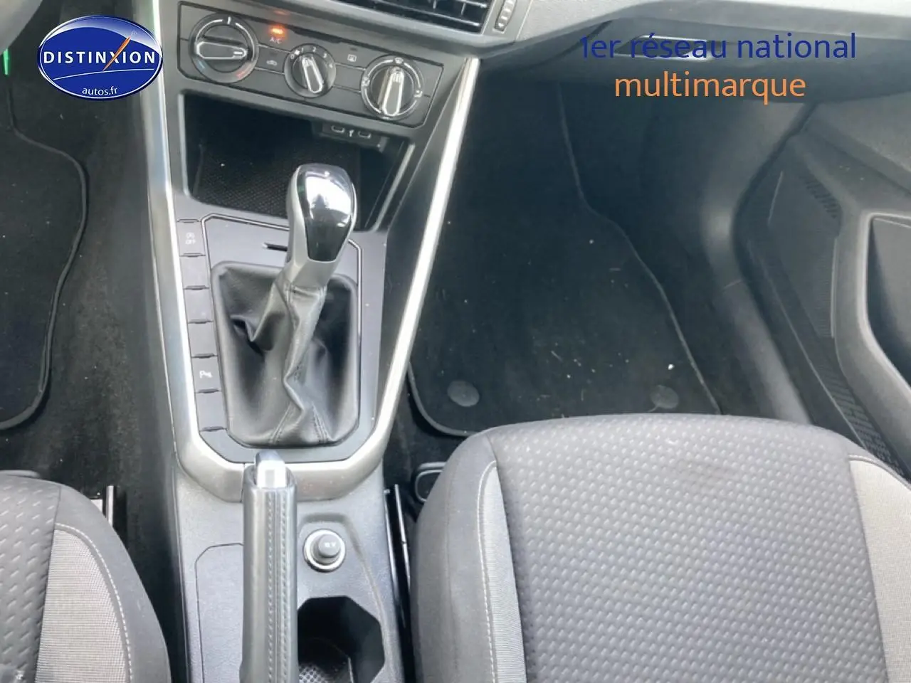 Vue intérieure centrée sur la console centrale et levier de vitesse d'une Volkswagen Polo 1.0 TSI gris cendre, sièges tissu noir.