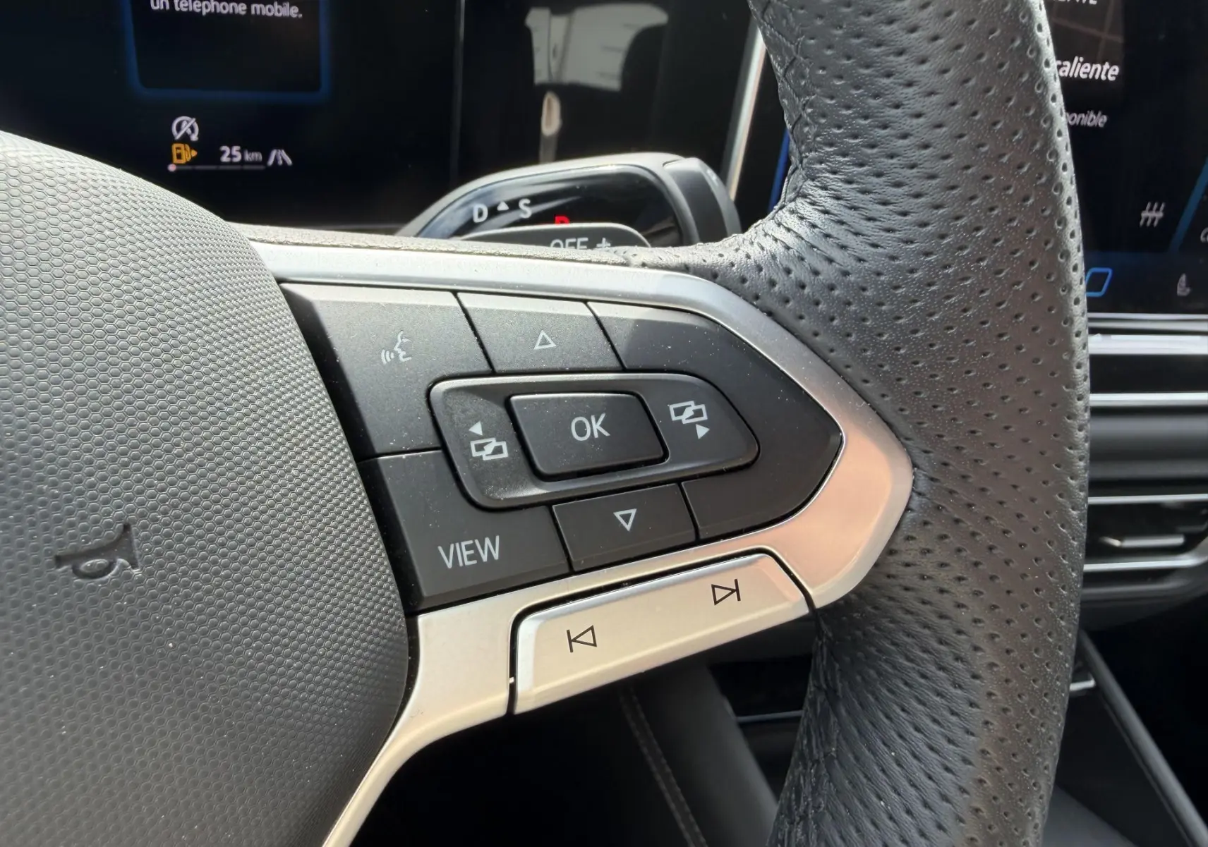 Gros plan sur les commandes multifonctions en cuir perforé du volant du Volkswagen Tiguan 2025, intérieur noir.