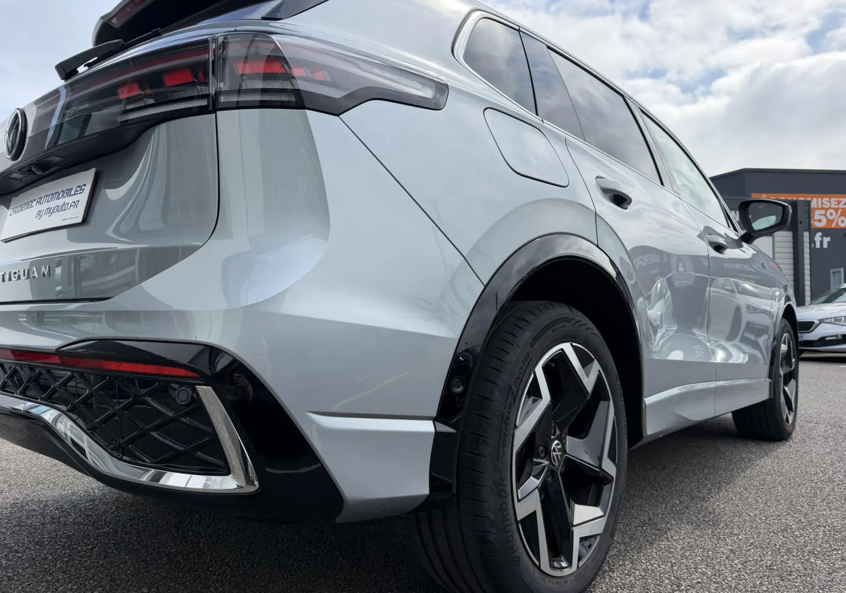 Vue 3/4 arrière droite du Volkswagen Tiguan gris 2025 avec jantes alliage noires et feux arrière LED 3D distinctifs.