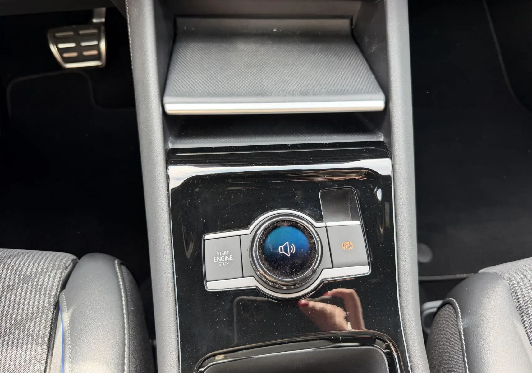 Vue plongeante sur la console centrale noire du Volkswagen Tiguan 2025 avec bouton Start/Stop et frein à main électronique.