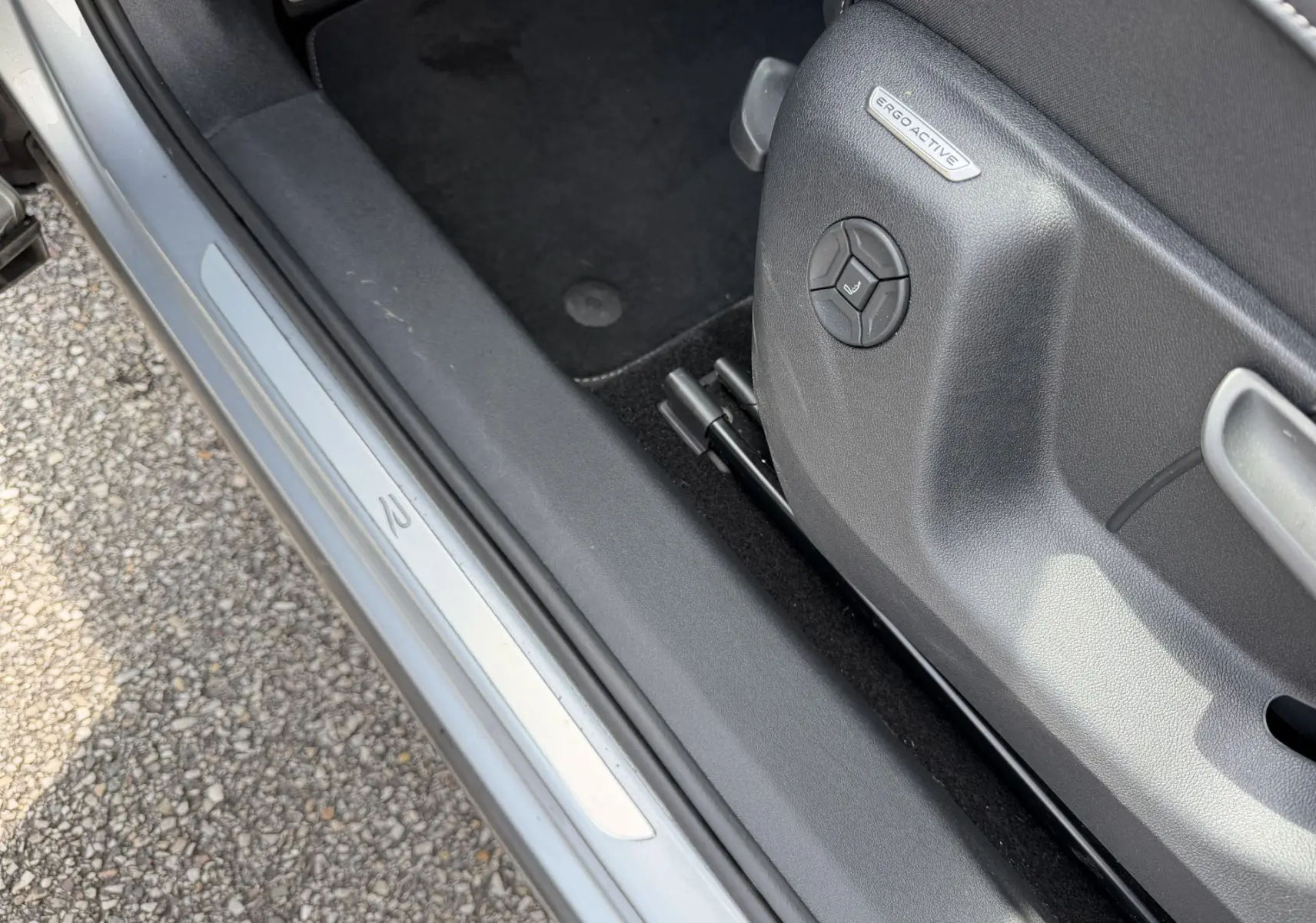 Détail de la porte côté gauche d’un Volkswagen Tiguan gris 2025 avec siège ErgoActive et seuil de porte R-Line.