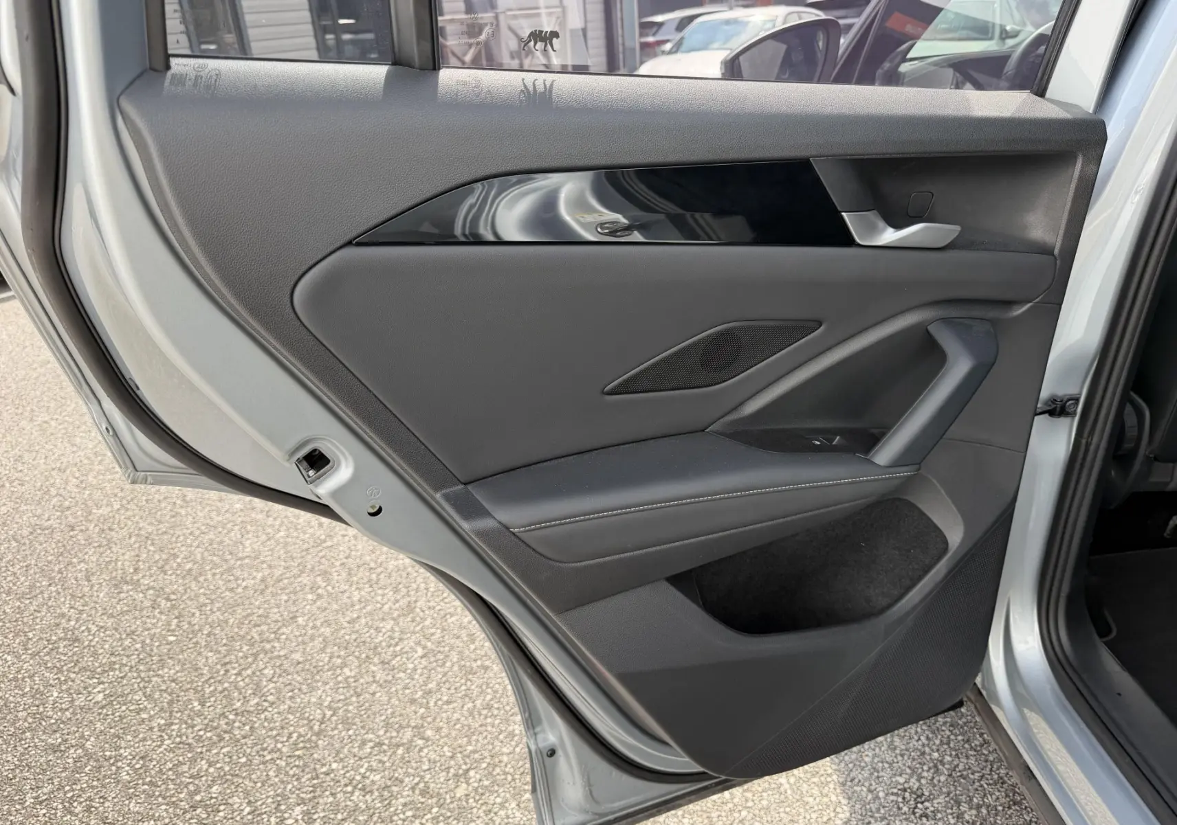 Vue rapprochée de la porte arrière gauche grise du Volkswagen Tiguan 2025, avec garniture noire et poignée argentée.