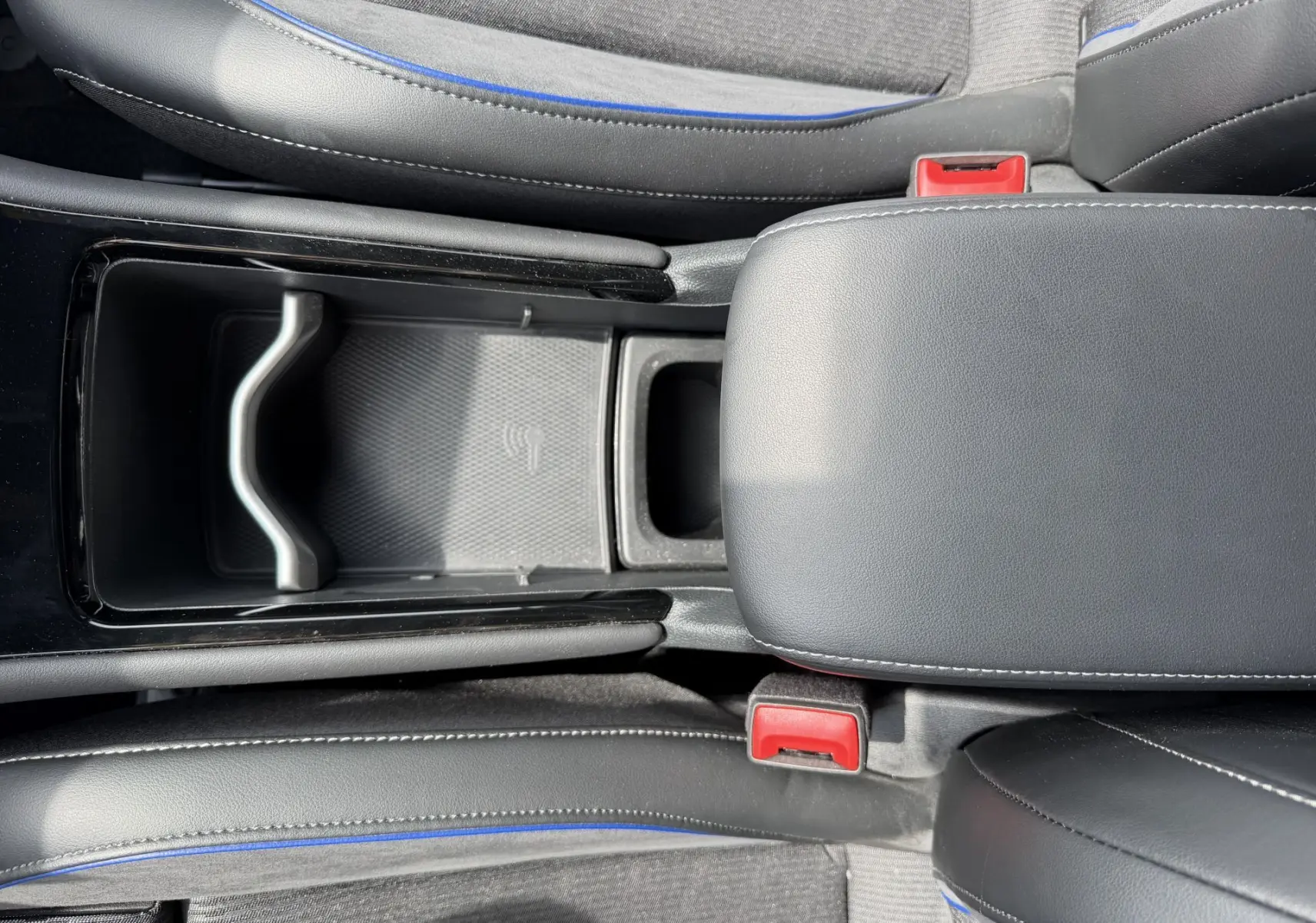 Vue plongeante sur la console centrale noire et les sièges gris avec surpiqûres bleues du Volkswagen Tiguan 2025.