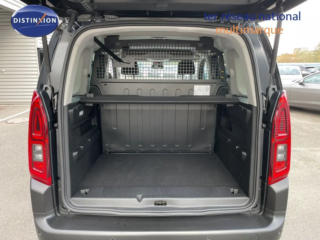 Coffre ouvert vu de l'arrière d'un Citroën Berlingo noir Perla Nera, montrant l'espace de chargement et la grille de séparation.