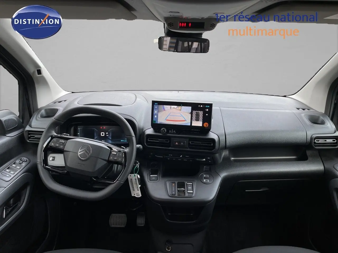 Vue intérieure avant du tableau de bord et volant du Citroën Berlingo noir, avec écran tactile affichant la caméra de recul.