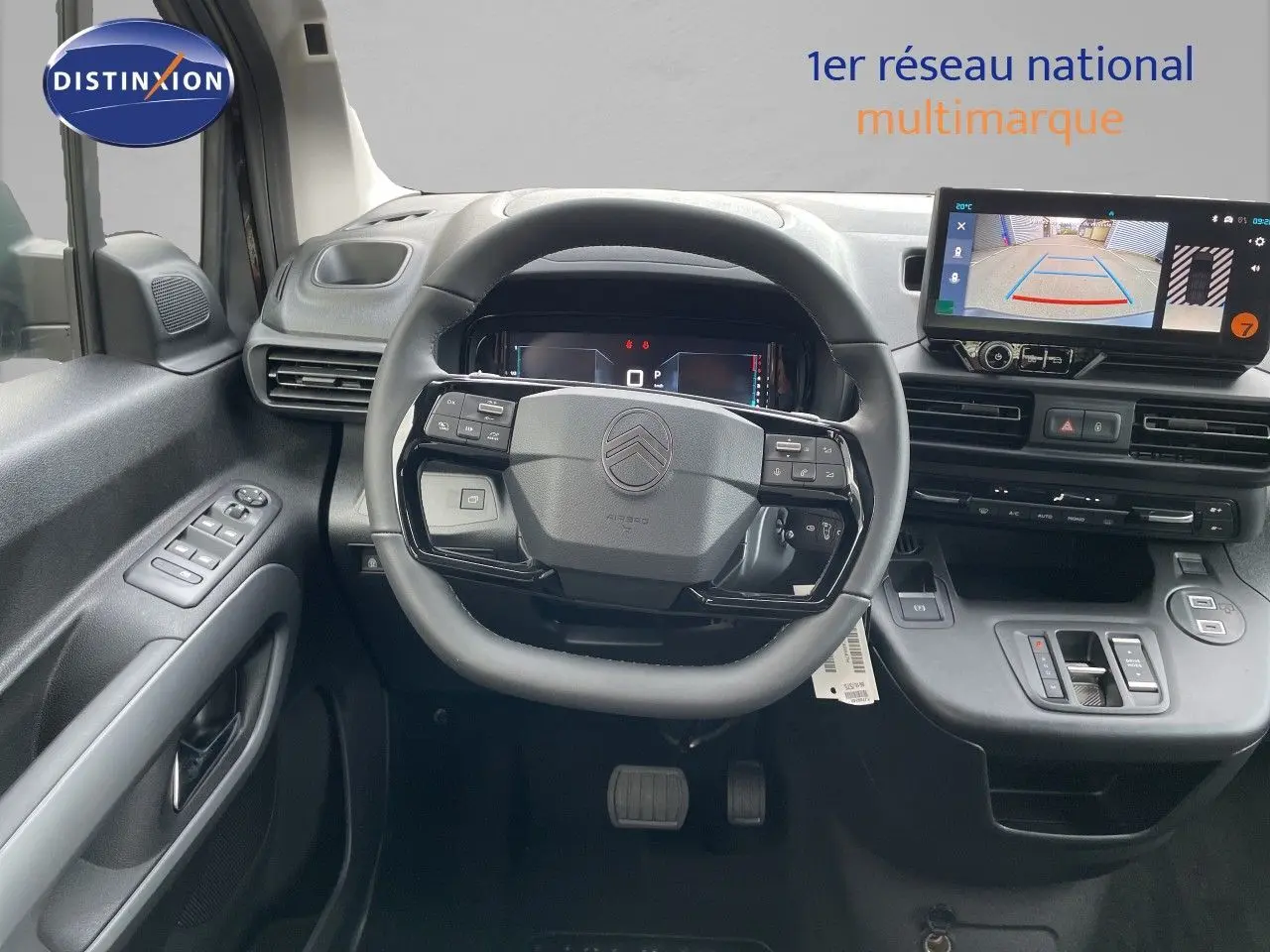 Vue intérieure frontale du poste de conduite du Citroën Berlingo noir, avec volant multifonction et écran tactile affichant la caméra de recul.