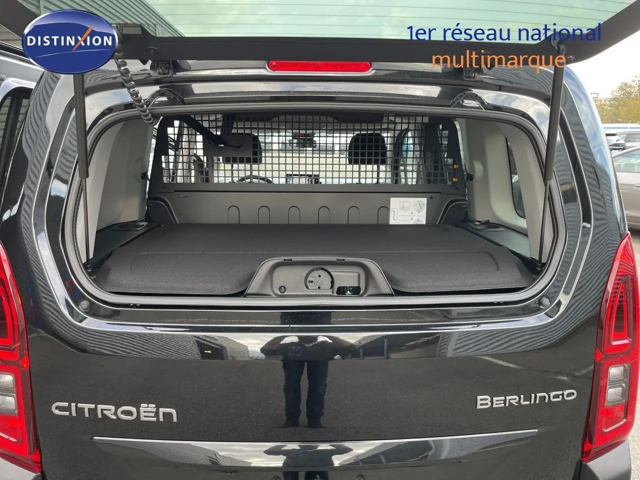 Vue arrière ouverte d'un Citroën Berlingo noir Perla Nera, montrant le coffre avec séparation grillagée et tablette de rangement.