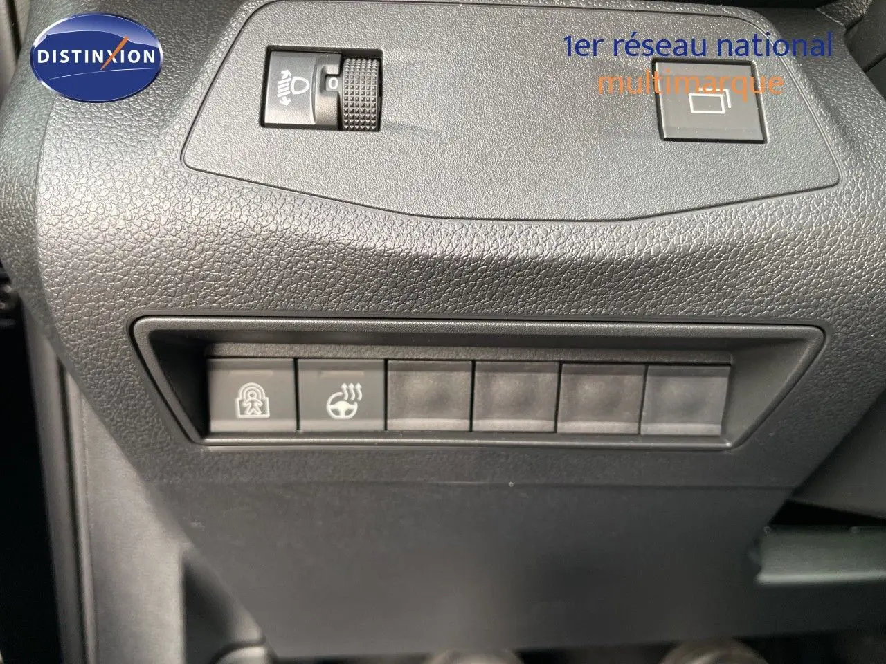 Gros plan sur les commandes de réglage de phares et de chauffage du volant dans un Citroën Berlingo noir intérieur, côté conducteur.