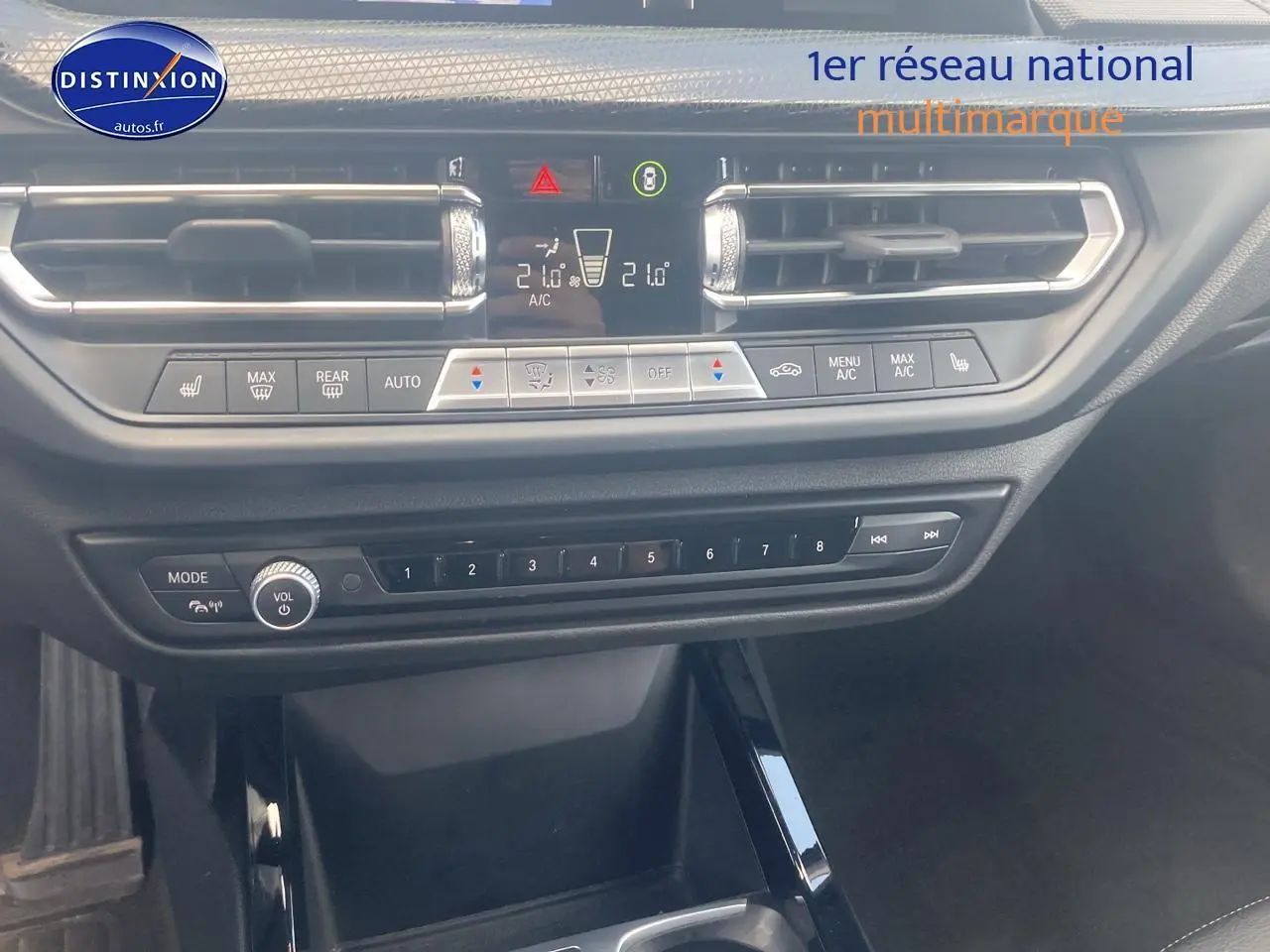 Vue rapprochée de la console centrale de la BMW Série 1 noire, montrant les commandes de climatisation et audio.