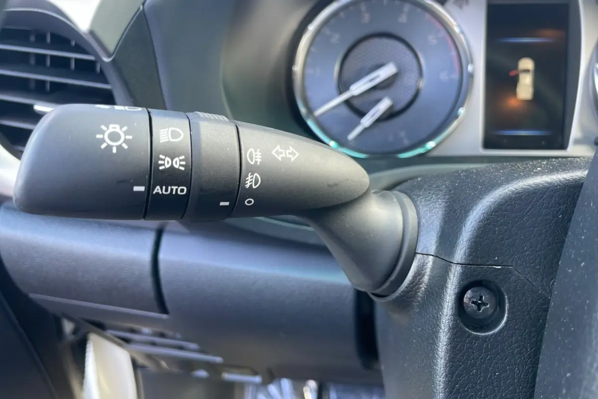 Gros plan sur la commande des phares du Toyota Hilux 4x4 2025, tableau de bord et compteurs en arrière-plan.