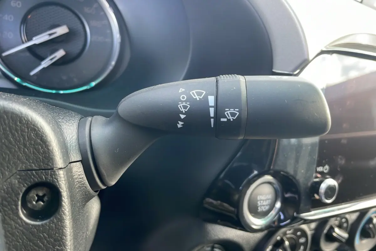 Gros plan sur la commande d’essuie-glace noire et le bouton start/stop dans l’habitacle du Toyota Hilux blanc 2025.