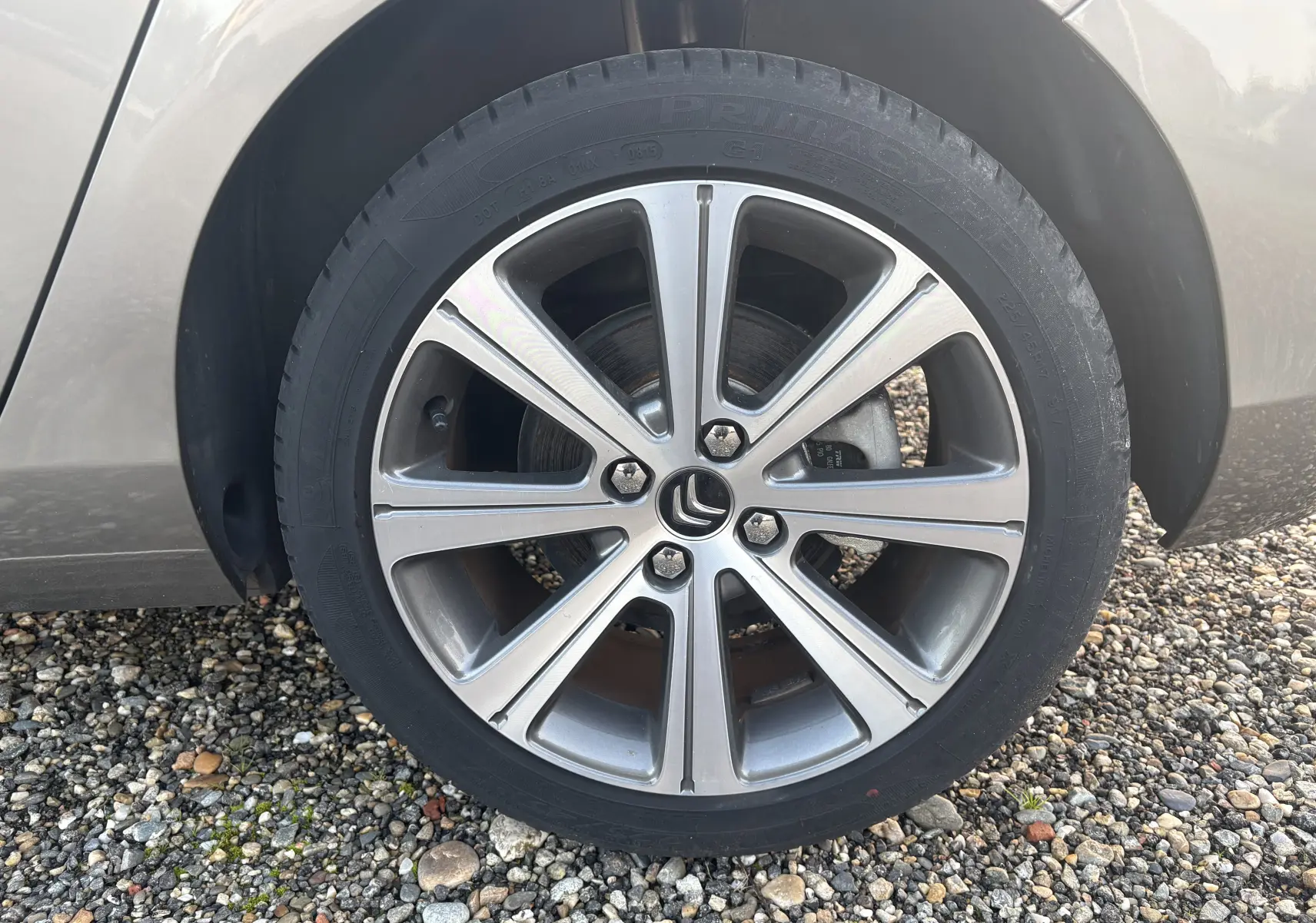 Gros plan sur la roue avant gauche d'une Citroën C4 gris clair, jante alliage à cinq doubles branches.