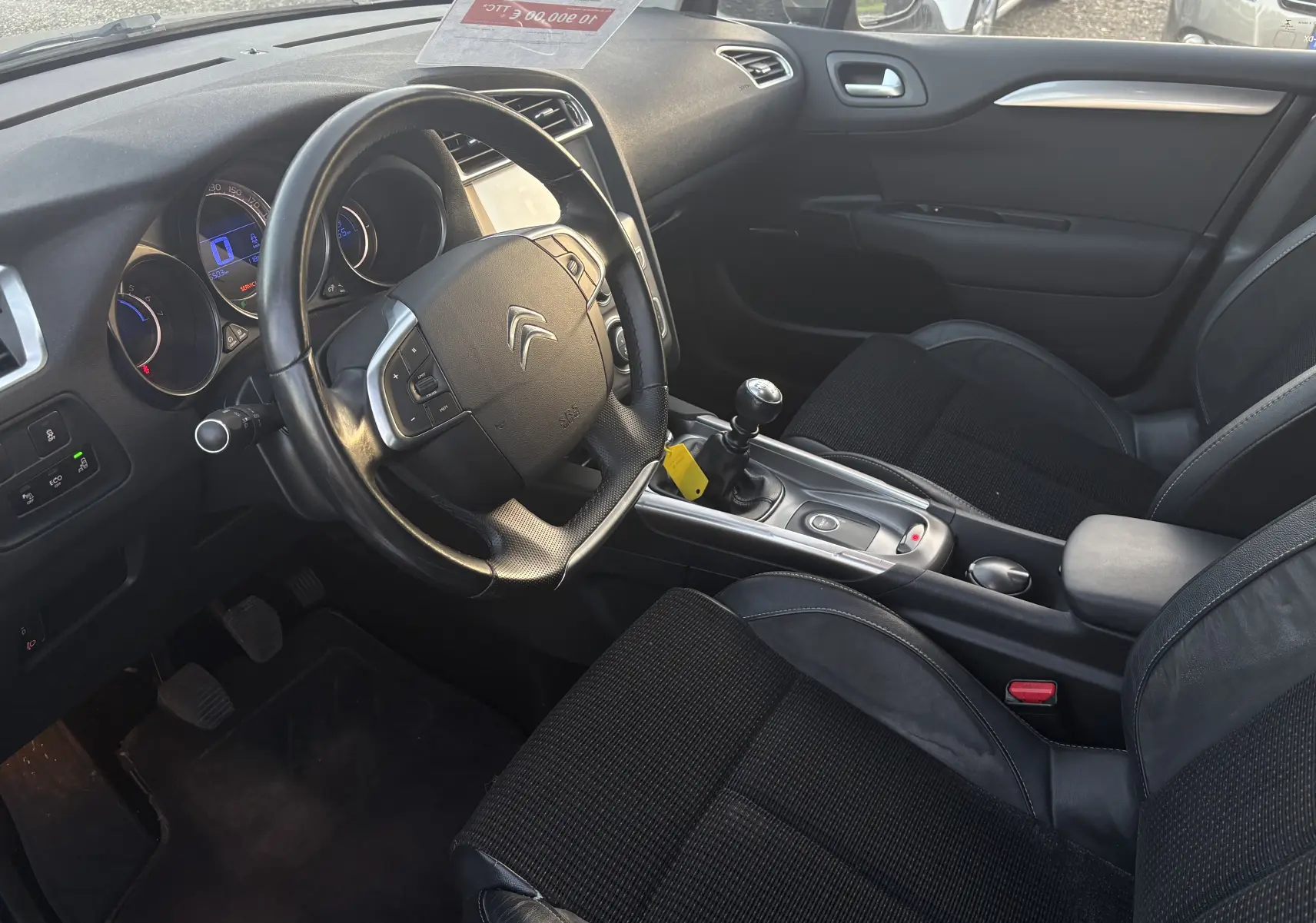 Intérieur noir de la Citroën C4 II 2.0 HDI 150 HYB 2015, vue côté conducteur avec volant et levier de vitesse manuel.