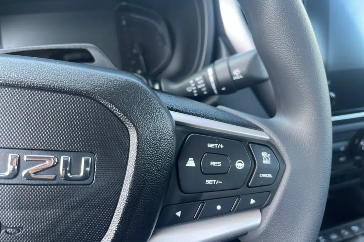 Gros plan sur le volant multifonctions noir de l'Isuzu D-MAX 2026 avec commandes de régulateur et assistance.