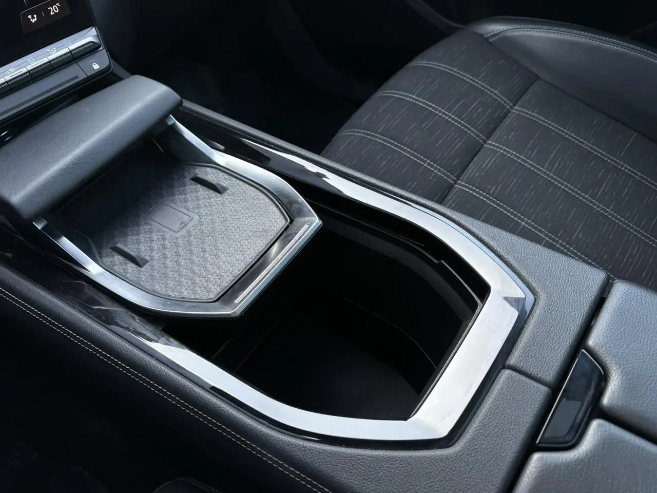 Gros plan sur la console centrale du Renault Austral E-Tech, montrant le chargeur sans fil et la sellerie tissu gris.