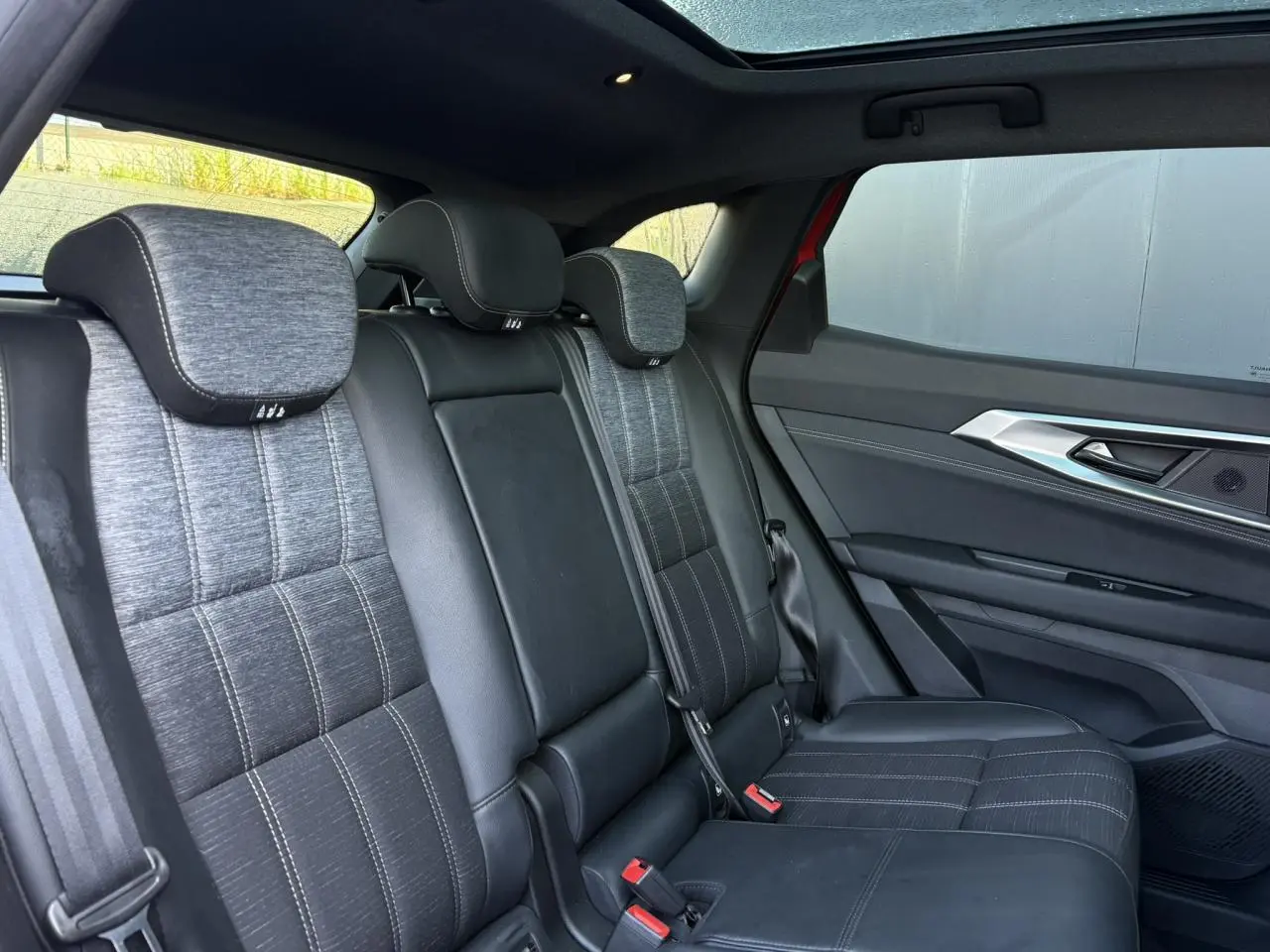 Vue intérieure arrière du Renault Austral E-Tech avec sièges mixte simili-cuir gris et toit panoramique en verre.