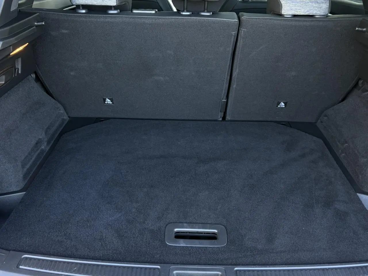 Coffre ouvert vu de l'arrière du Renault Austral E-Tech Full Hybrid 2024, intérieur noir avec sièges rabattus.