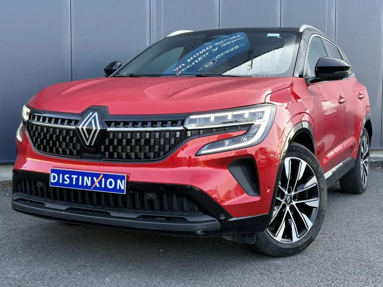 Renault Austral rouge Flamme en 3/4 avant droit, avec calandre noire et jantes alliage 19 pouces distinctives.