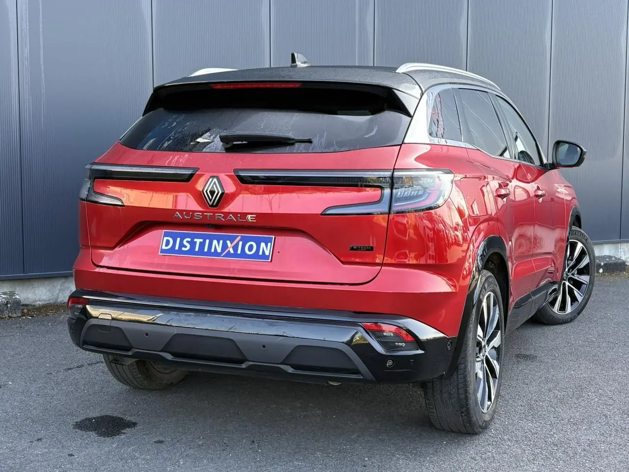 Vue 3/4 arrière droite d'un Renault Austral rouge Flamme avec toit noir étoilé et jantes alliage 19 pouces.