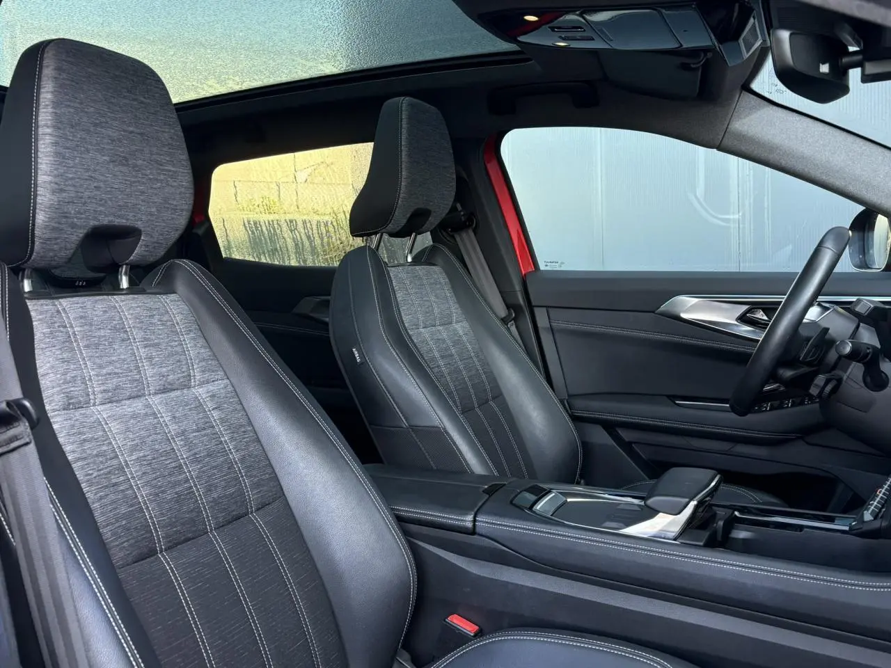 Intérieur du Renault Austral E-Tech 2024 montrant les sièges avant en simili-cuir gris et toit panoramique ouvert.