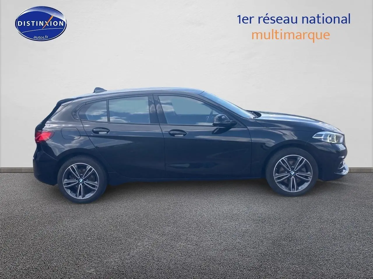 Profil côté gauche d'une BMW Série 1 noire édition sport 2023 avec jantes alliage et vitres teintées.