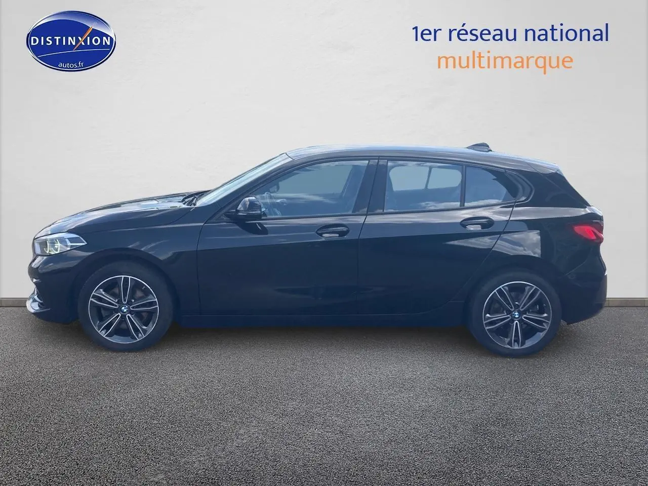 Profil latéral gauche d'une BMW Série 1 noire 2023 avec jantes alliage 17 pouces et lignes sportives marquées.