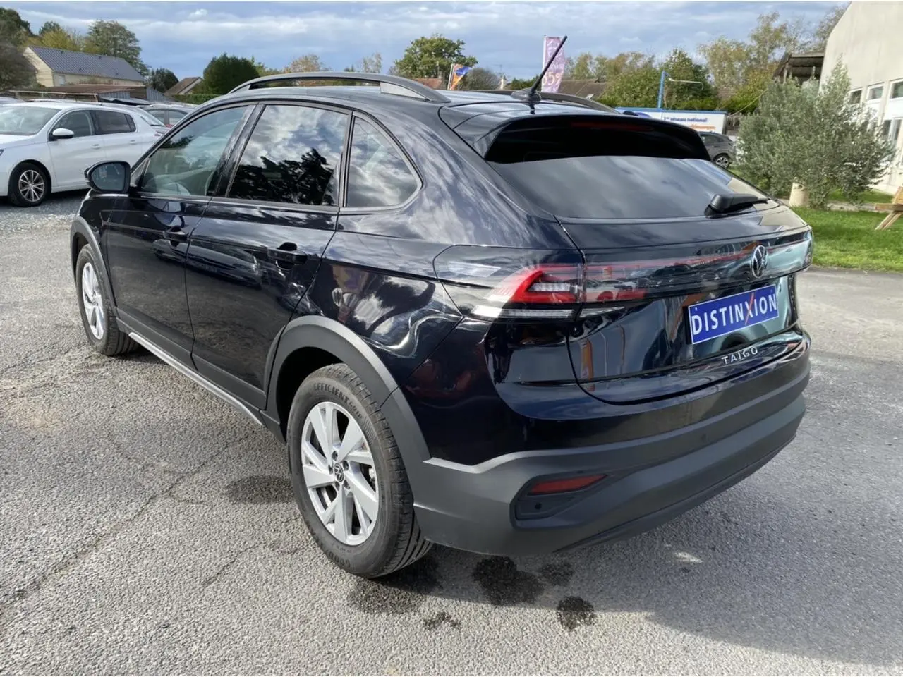 Vue 3/4 arrière droite d'un Volkswagen Taigo noir intense avec feux arrière allongés et jantes argentées.