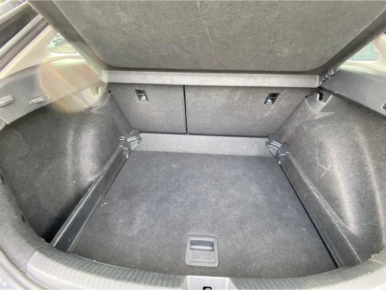 Coffre ouvert en vue plongeante d'un Volkswagen Taigo noir intense, montrant un espace de chargement propre et vide.