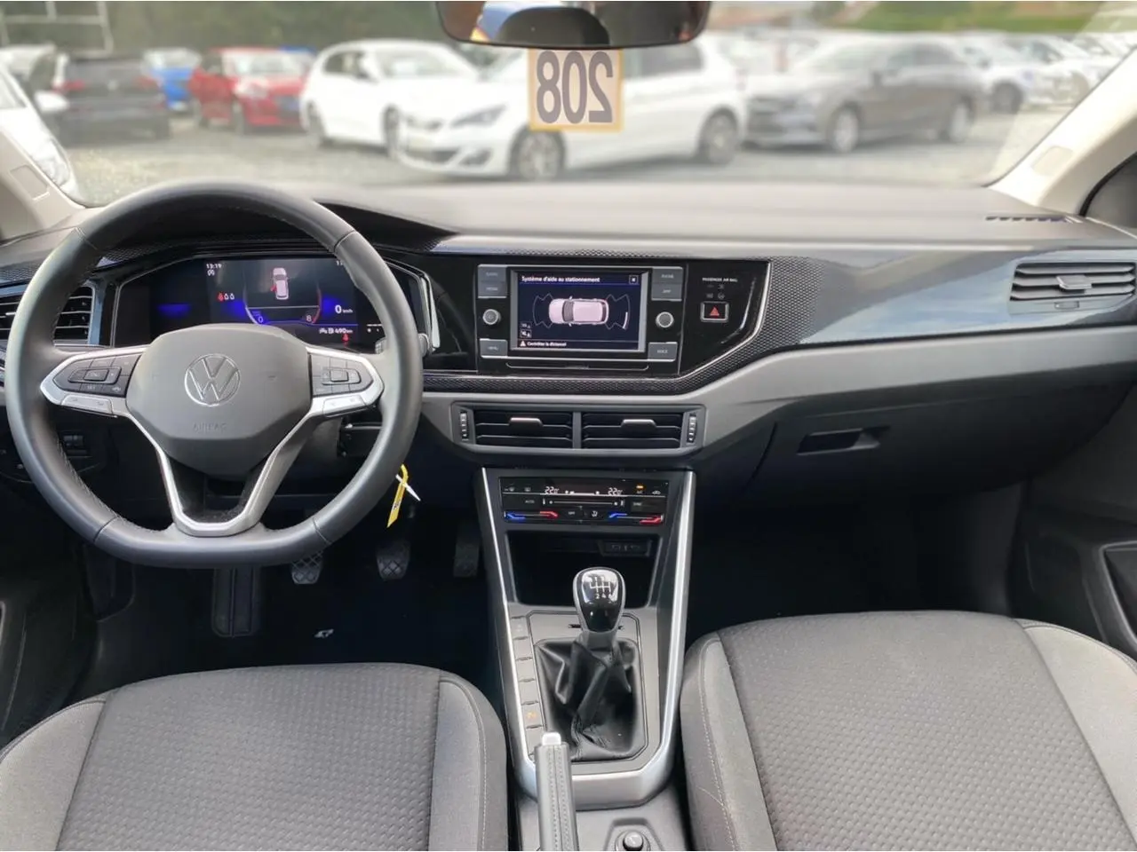 Intérieur de Volkswagen Taigo 2022 noir intense, vue frontale du tableau de bord avec écran tactile et boîte manuelle.