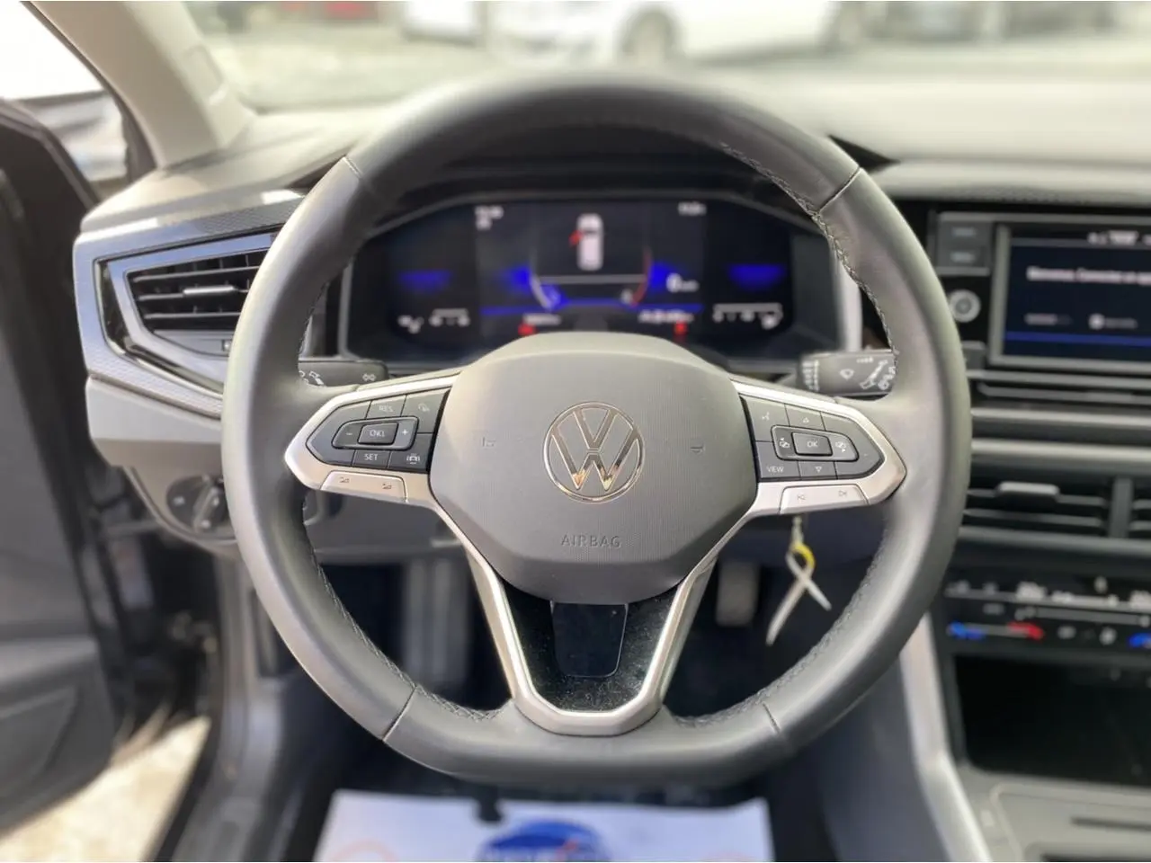 Vue rapprochée du volant noir du Volkswagen Taigo 2022 avec commandes intégrées et tableau de bord numérique.