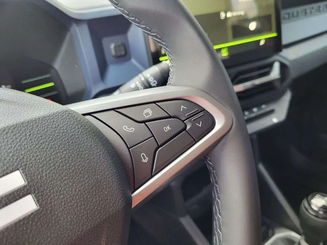 Gros plan sur les commandes au volant du Dacia Duster 2025, version TCE 130 4X2 Journey, avec finition noire et surpiqûres.