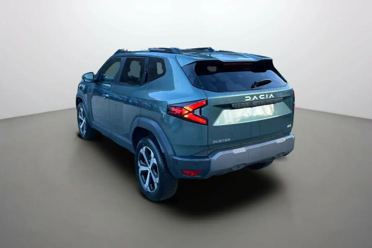 Vue 3/4 arrière droite du Dacia Duster 2025 vert cèdre avec feux arrière en forme de flèche et jantes alliage.