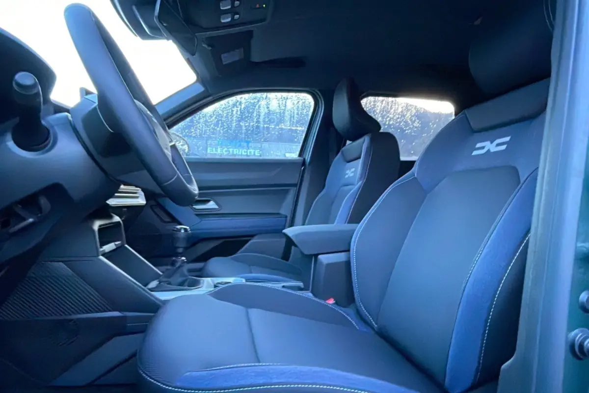 Vue intérieure côté conducteur du Dacia Duster TCE 130 4x2 Journey 2025 avec sièges noirs et logo DC brodé.