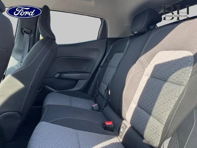 Vue latérale intérieure montrant la banquette arrière en tissu gris et noir de la Renault Clio 1.6 E-Tech hybride 2023.