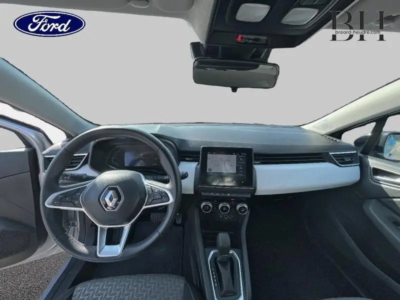 Vue intérieure avant de la Renault Clio 1.6 E-Tech hybride 2023, tableau de bord gris avec écran tactile central et volant multifonction.