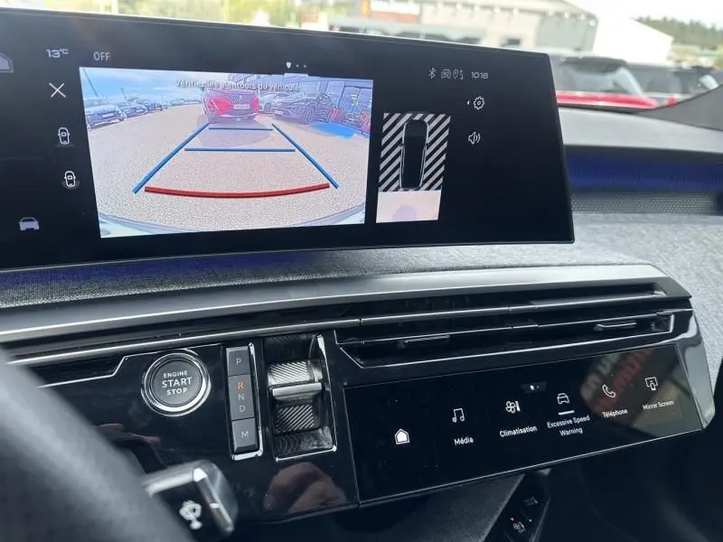 Vue intérieure du tableau de bord du Peugeot 3008 2024 gris métal, avec écran de recul et commandes tactiles visibles.