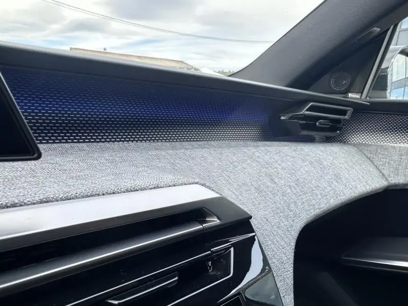 Détail intérieur côté passager du Peugeot 3008 2024 hybride, avec tissu gris et bandeau décoratif texturé bleu.