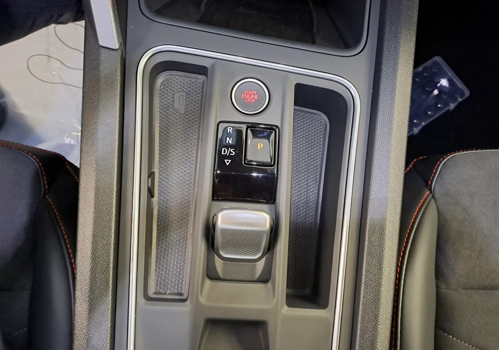 Gros plan sur la console centrale de la SEAT LEON 2024 noir minuit, avec levier de boîte auto et bouton start/stop rouge.