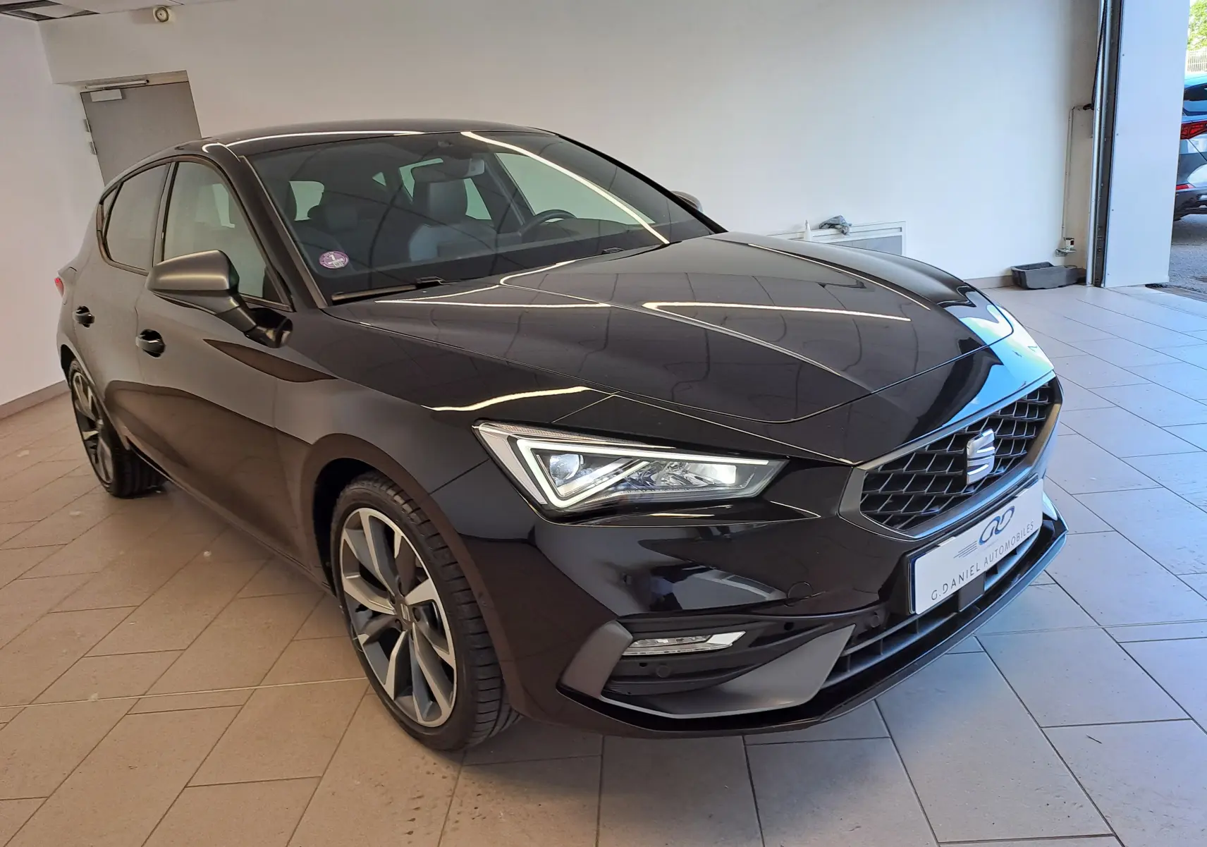 SEAT Leon 1.5 eTSI Hybrid 2024 en noir minuit, vue 3/4 avant mettant en valeur les phares LED et la calandre distinctive.