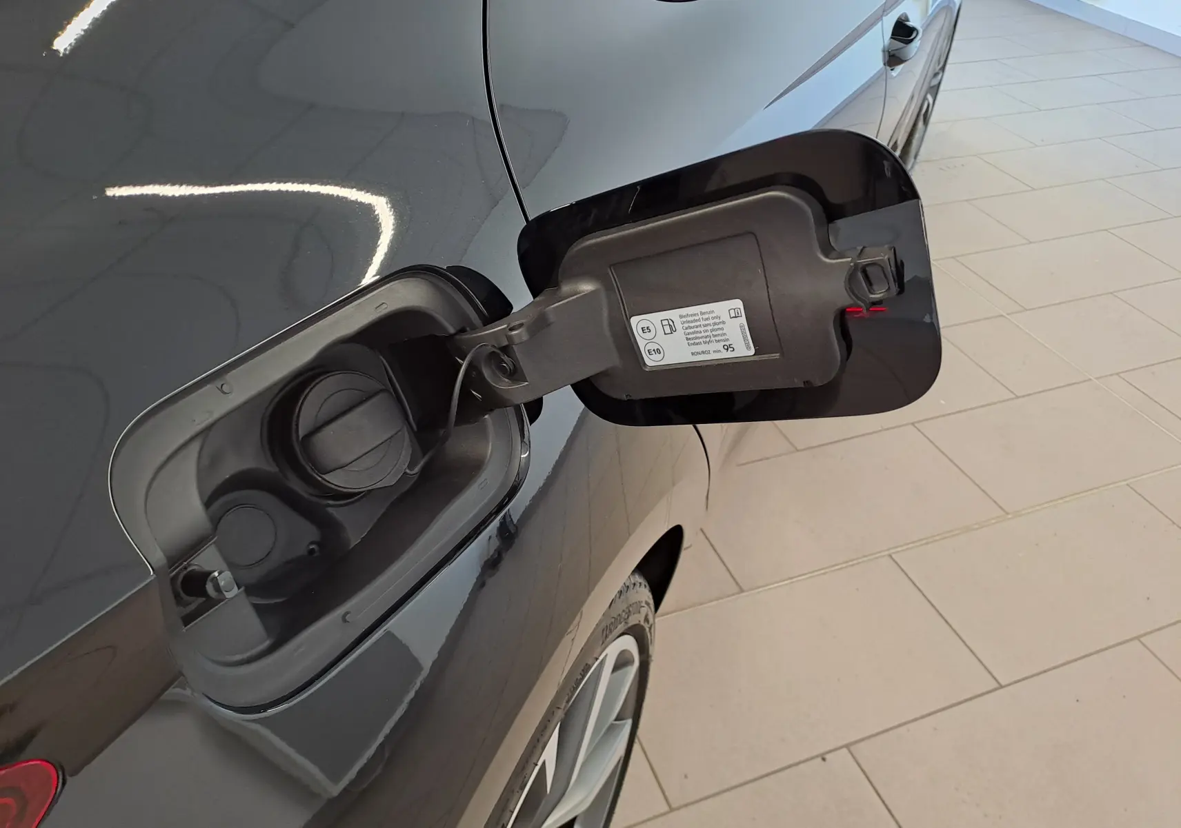 Bouchon de réservoir ouvert côté gauche d'une SEAT LEON 1.5 eTSI Hybrid noir minuit, vue rapprochée sur la trappe à carburant.